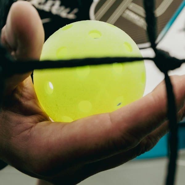 Placeholder texture crop of a pickleball against net mesh. A real photo from each gym replaces this before launch.